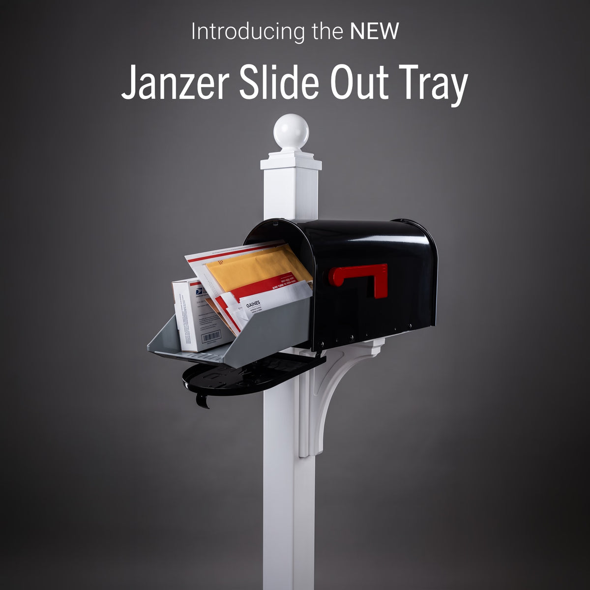 A black Janzer slide-out mail tray mounted on a white mailbox post, shown with an open black mailbox and mail inside against a dark gray gradient background. White text at the top reads 'BACK BY POPULAR DEMAND the Janzer Slide Out Tray.