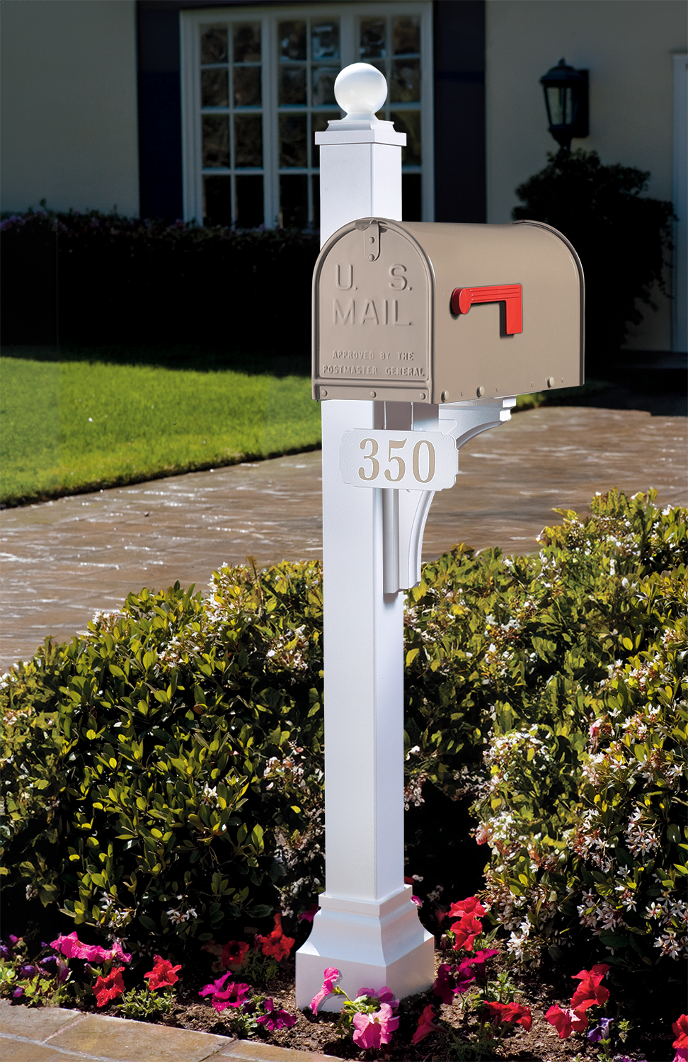 Premium beige mailbox with classic red flag, set on a sturdy white post, enhances curb appeal amid lush landscaping.